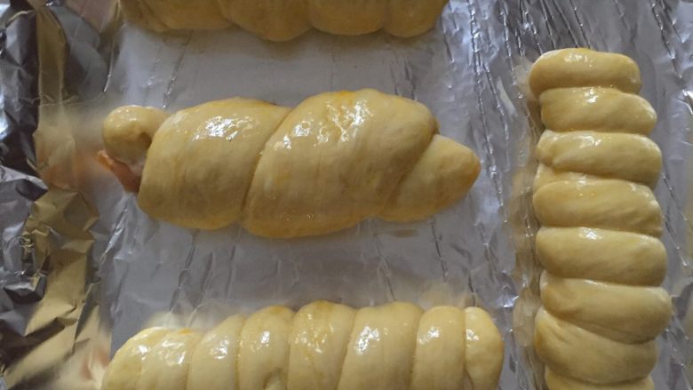 火腿肠卷面包,取一个中间发酵好的面团，在案板上搓成细长的面条。卷在<a style='color:red;display:inline-block;' href='/shicai/ 437'>火腿肠</a>上，再发酵40分钟，在表面涂上全蛋液