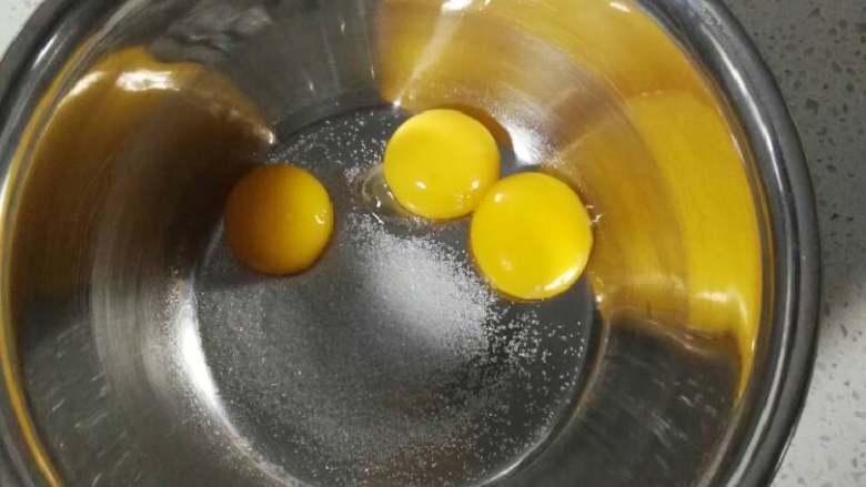 紫薯慕斯蛋糕,蛋白蛋黄分离,蛋黄加入5克细砂糖,用打蛋器打散,砂糖融化。