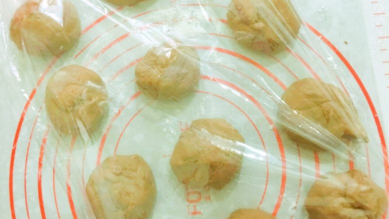 好吃到飞起来的黑眼豆豆,取出面团,排气,分成50g左右的小面团,揉成团,盖上保鲜膜醒发一刻钟左右。