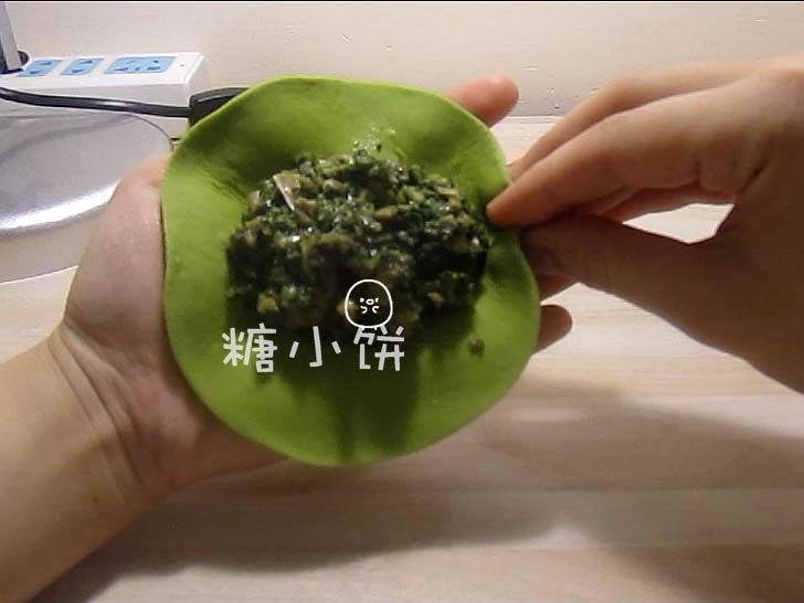 菠菜柳叶包,一只手托着面皮,另一只手的大拇指和中指捏着外面,食指抵着里面,大拇指和中指向食指处一捏形成最初的褶子。
