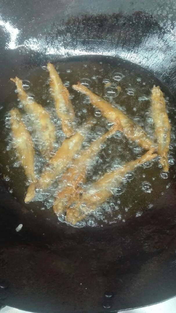 椒盐多春鱼,多春鱼撒上味精,裹上脆浆,下油锅炸至熟透金黄色捞出。