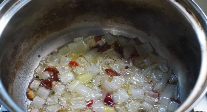 响油土豆片,锅中热油,把大葱和辣椒粒爆出香味。