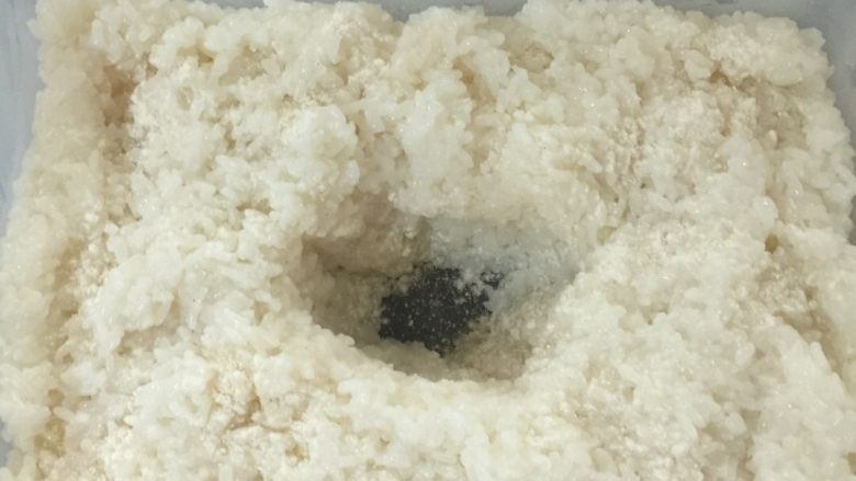 甜酒酿--家庭简单版,铺好所有糯米饭,再把剩余的酒药撒上最上面,再用饭勺挖一个坑!