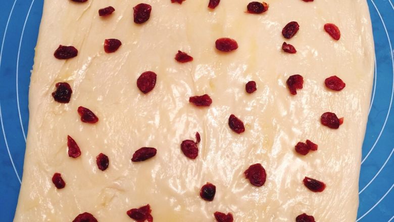 蔓越莓面包,放揉面垫上松弛15分钟后擀成长方形均匀的抹上混合酱（辅料中的黄油和<a style='color:red;display:inline-block;' href='/shicai/ 893'>炼乳</a>放微波炉加热20秒搅拌均匀成混合酱），再撒入少许蔓越莓（混合酱和蔓越莓要留一点后面用）