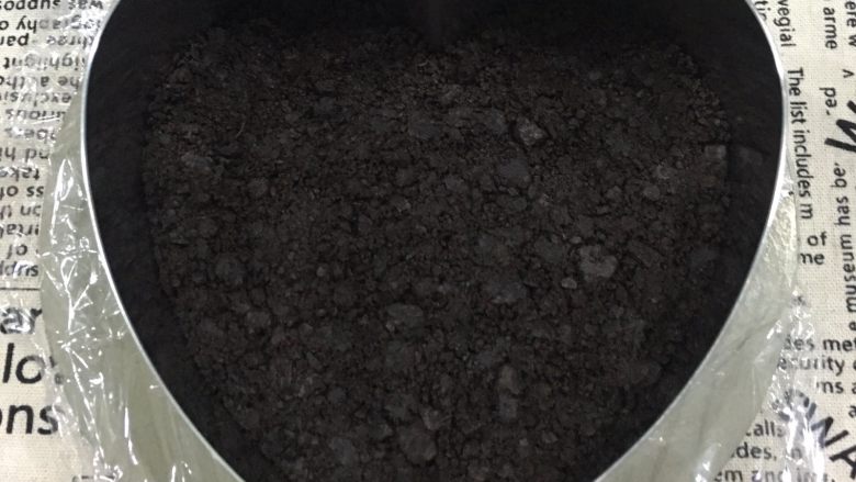 免烤芒果慕斯蛋糕,慕斯圈底部包上保鲜膜,将拌好的饼干碎铺入慕斯圈底部,压实后送入冰箱冷藏备用。