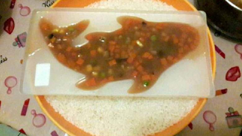 皮冻鱼🐟,肉皮煮熟后再把其他食材也加入一同再煮五分钟,这时的汤汁应该是浓稠的,最后再调好整一下口味,感觉味道符合自己了后把皮冻混合糊倒入到抹好油的模具内放入冰箱冷藏塑型,为了保持平衡我把模具倒放置在盛满大米的盆内。