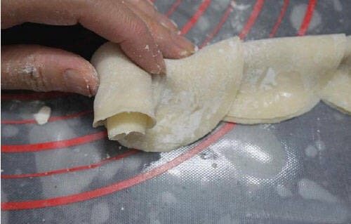 玫瑰花煎饺,将对折的饺子皮,从一端轻微的卷起,卷好接口处,捏好,保证地步平坦