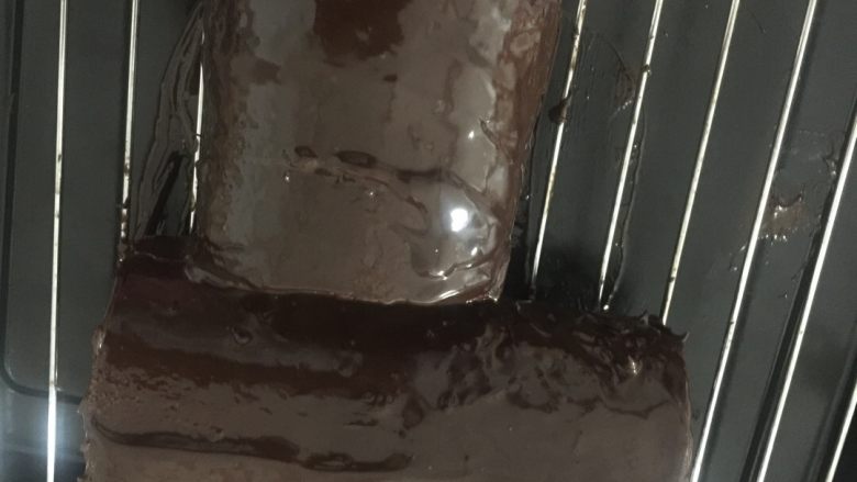 树干蛋糕,取出蛋糕卷,分成一长一短的两段
摆成如图所示的样子
然后把巧克力液淋到蛋糕上
全部包裹住蛋糕体。
我是把蛋糕体放到了一个烤架上
下面垫了一个烤盘
这样流下来的巧克力液可以收集起来继续用