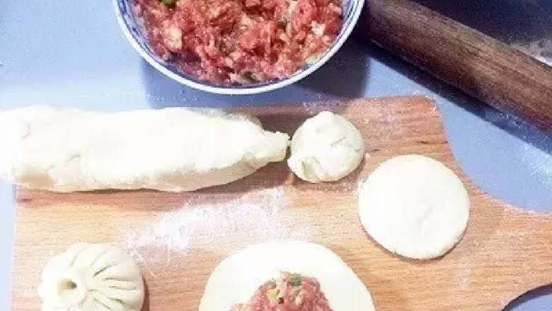 肉包子,把揉好的面团整成长圆形,用手揪一个个剂子下来,按扁后用擀面杖擀成中间稍厚的圆形皮子,然后捏出褶子包好(我包得不好看大家不要笑啊😄)