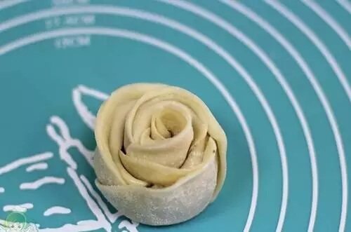 玫瑰花煎饺,从一端卷起,末尾交接出沾点水粘连稳固,这样就成了一朵玫瑰花