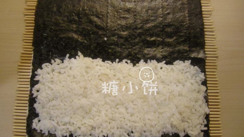 玉米笋细卷,在靠下端的一半铺上米饭。因为是细卷,米饭不要铺太多,一半就够如果用半张紫菜的话还可以再少铺一点,堪堪够包裹住夹馅的食材就行。