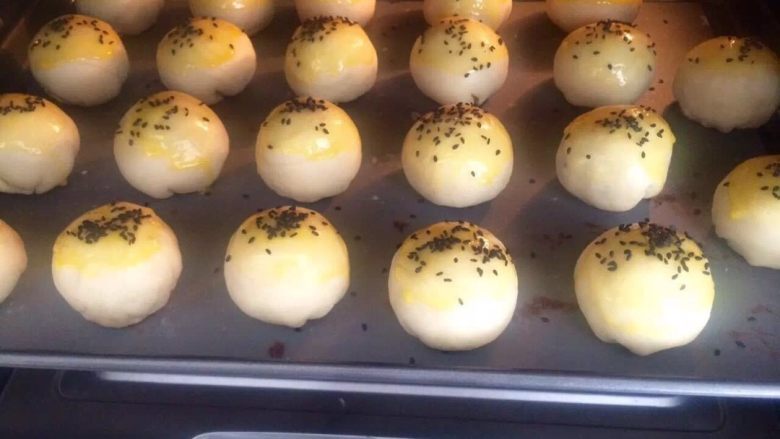 苏式月饼,7.把豆沙咸蛋黄包入擀圆的油皮中；表面刷蛋黄液，撒上黑芝麻；
8.放入烤箱上下火180度，烤制30分钟。