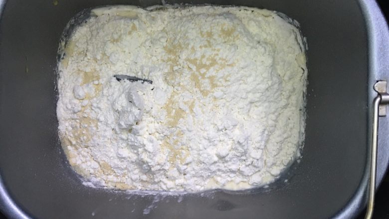乳酪火腿面包,除黄油以外的所有面团材料按先液体后粉类的顺序投入面包机,启动一个和面程序。