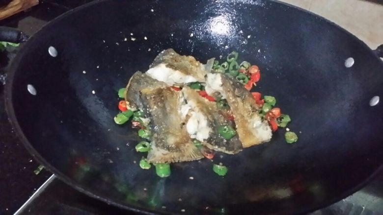 青红椒煎焖鲩鱼,加入适量花生油,爆炒至呈虎皮状,倒入鱼块,加适量清水、生抽,盖锅盖焖煮至收汁。