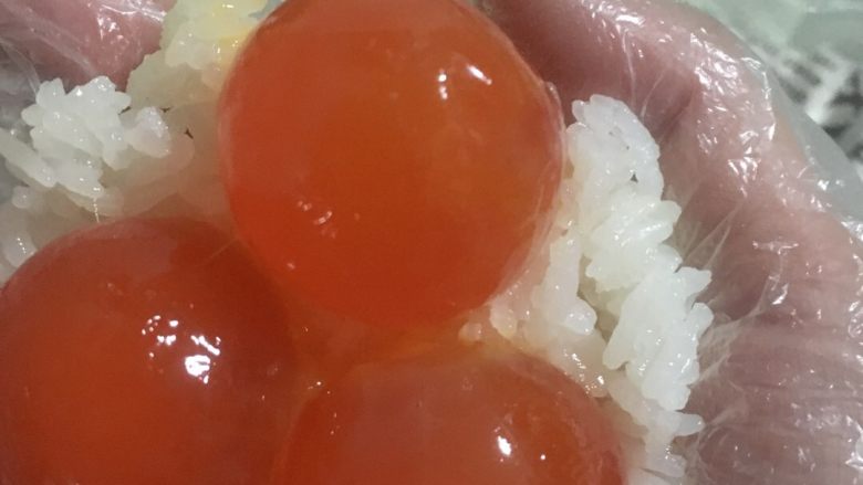 蛋黄肉松糯米饭,三个蛋黄排好，抓过一团糯米饭固定，不可全部包住，要露出起码三分之一的蛋黄