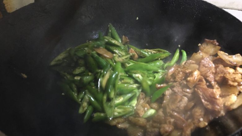 农家小炒肉 湘菜,把上好色的肉拨到一旁，<a style='color:red;display:inline-block;' href='/shicai/ 62'>辣椒</a>入锅。开始翻炒。看到<a style='color:red;display:inline-block;' href='/shicai/ 62'>辣椒</a>慢慢熟了，加大葱段。再次翻炒。