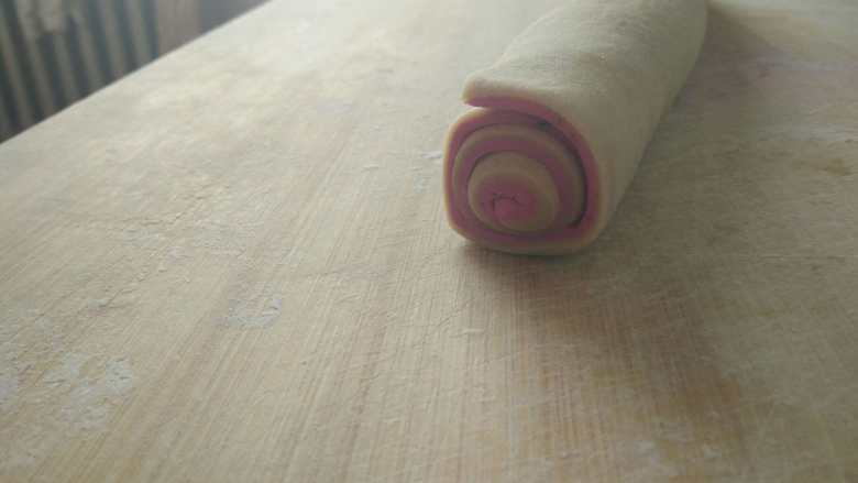 双色猫耳朵,将紫色面片放到白色的上面，卷起来，尽量卷的紧一些，然后包上保鲜膜放到冰箱冷冻室冻15-20分钟。