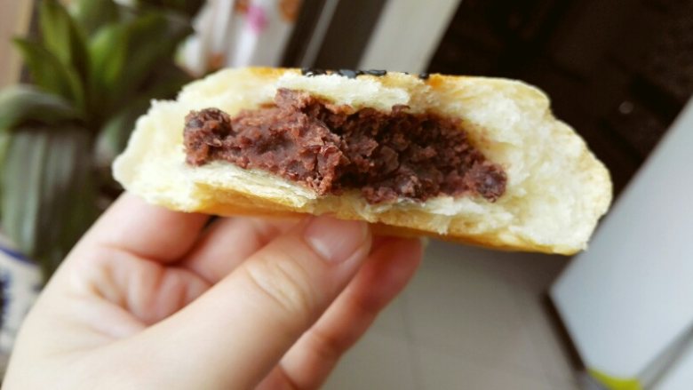 红豆包,包好的豆包用保鲜膜盖住,放在烤盘上最后放温暖处发酵,发酵好的豆包撒上黑芝麻。找一张油纸盖在豆包上,拿一个烤盘压在油纸上。用手按几下,把豆包压扁就行了。