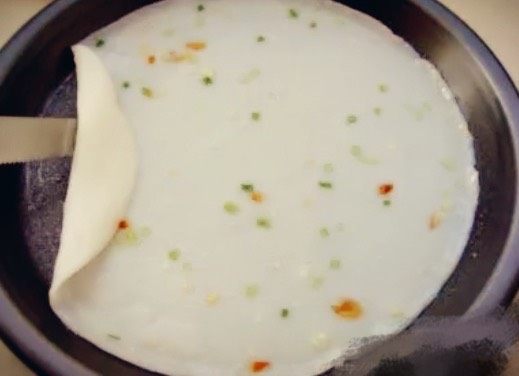 水晶虾仁肠粉,蒸锅里的水大火烧开,盘子里刷上薄薄的一层油,把拌好的米汤浇在盘子里,大火隔水蒸三到五分钟,拿出来稍事冷却,粉皮里放上虾仁,卷起来