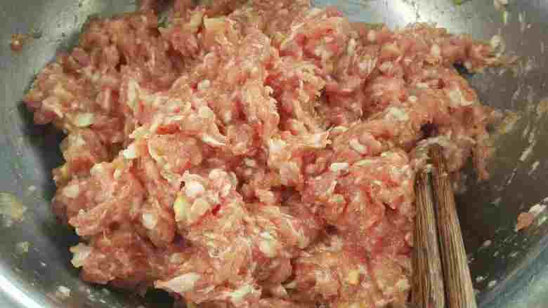 年味炸肉丸子,把混合在一起的肉馅用四根筷子顺着一个方向搅拌,搅拌起劲后放下备用。
