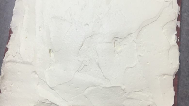 红丝绒棉花蛋糕卷,把奶油涂抹在蛋糕胚表面,靠近身体这一侧的奶油多放一些,卷起来才好看,厚厚的,临近卷起接拢的那一端不涂也可以,免得奶油溢出来