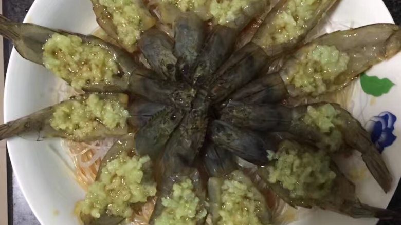 开背蒜蓉虾,粉色铺地,虾摆盘,在虾背上逐个放入蒜蓉,并将腌制虾的碗汁均匀倒在虾上。