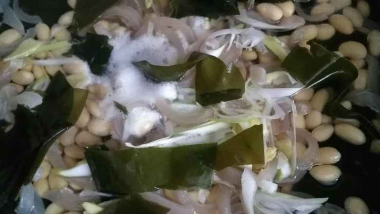 家常酱海带黄豆,锅内温水,放入肉皮、海带和黄豆,以及葱和姜。
