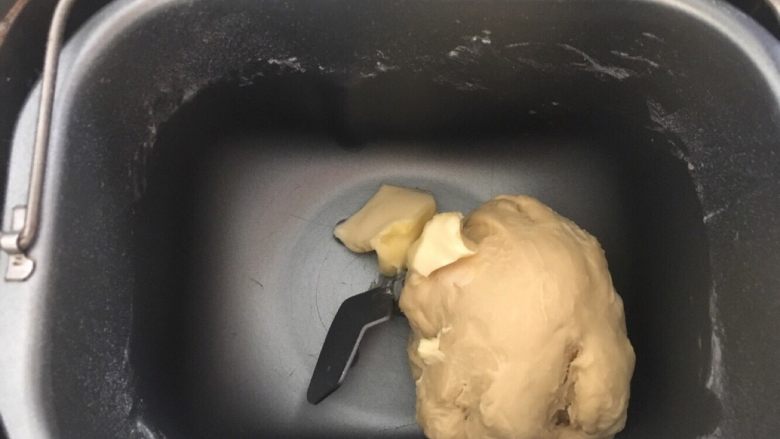 蓝莓夹心网纹面包,和面十分钟左右的时候面团就光滑了,这时候把黄油投入面包桶,继续和面