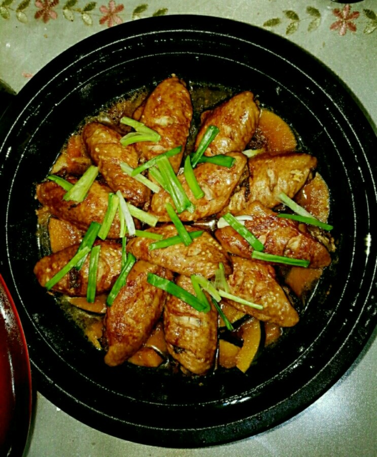 南瓜焖鸡翅（来自食谱，塔吉锅真的很牛，10分钟完全搞定）,最后撒上<a style='color:red;display:inline-block;' href='/shicai/ 157'>小葱</a>做装饰，出锅，上桌，鸡肉细腻鲜美还不硬，味道很棒，有南瓜和胡萝卜的丝丝甜味，我们家的小朋友直说:好吃，家里来的客人称赞:地道！老妈老爸也爱吃，真的很受大家欢迎呢
