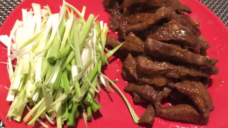 牛肉蒜苗卷饼,蒜苗白切丝,腌好的牛肉炒熟,装盘。