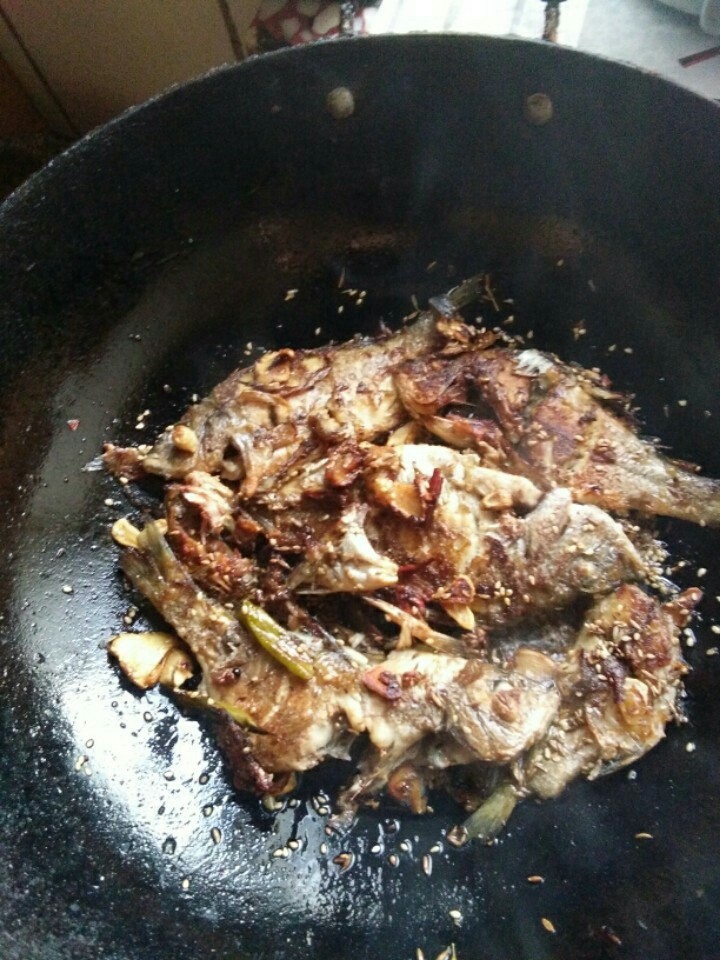 啤酒烤鱼,加入煎好的鱼,还是小火慢慢翻动煎至有干香时加入白糖,芝麻,孜然粒。