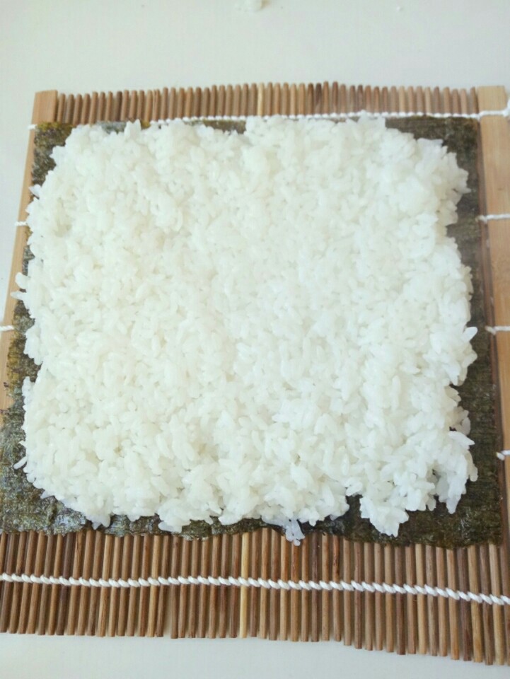 寿司,寿司帘洗干净，放在干净的菜板上，然后取一张<a style='color:red;display:inline-block;' href='/shicai/ 279'>海苔</a>铺在寿司帘上，然后将米饭均匀的铺在<a style='color:red;display:inline-block;' href='/shicai/ 279'>海苔</a>上，不要太厚，大约5cm厚度就可以