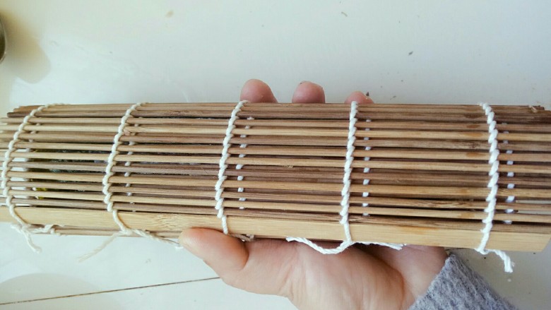 寿司,然后开始从下往上卷,卷的时候注意不要把帘子卷进了饭里哦,要一边卷,一边往上拉竹帘,卷好后用力握几下,固定下形状,防止切的时候变形散掉!(因为一个人做,不方便拍这部,大家做的时候注意下就可以)