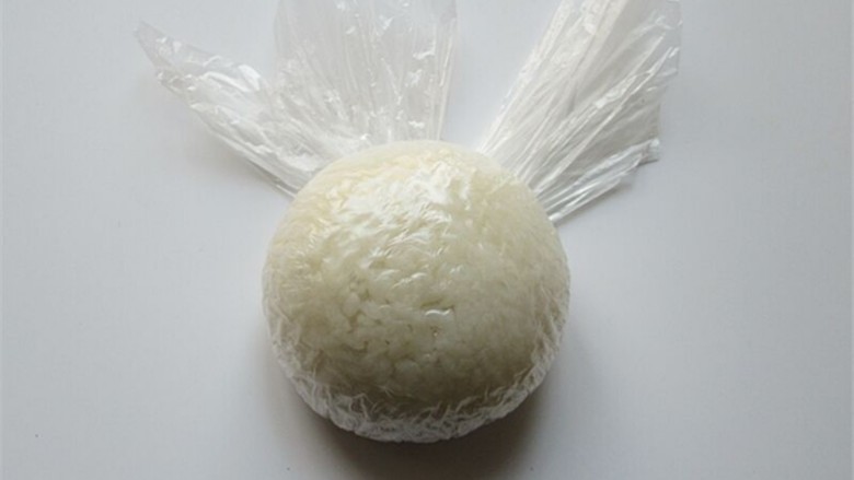 米菲兔杯子趣味餐,把米饭用保鲜膜握紧团起来,揉成一个球形饭团做头部主体部分