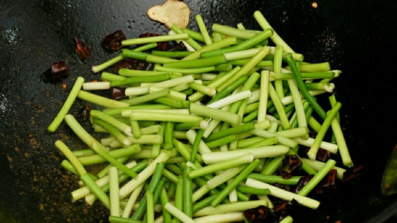 蒜苔肉丝#春意绿#,辣椒微糊放入蒜苔,炒至断生。