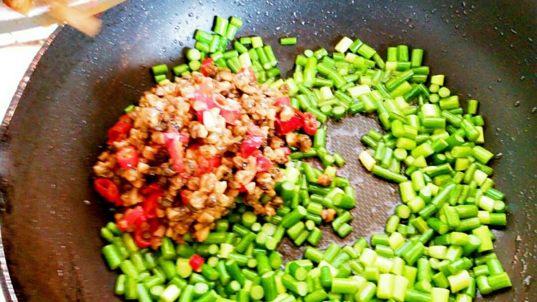 蒜苔炒螺丝肉(香辣版),蒜苔炒三分钟后基本熟透,接着把刚才炒好的螺丝肉倒入锅内