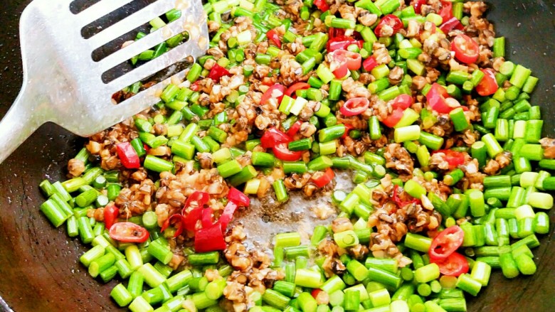 蒜苔炒螺丝肉(香辣版),再用锅铲把螺丝肉和蒜苔一同炒制半分钟左右。