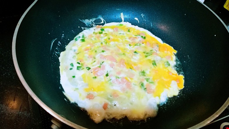 快手早餐——鸡蛋火腿肠芝士煎饼,用勺子把鸡蛋抹到面糊上,摊匀