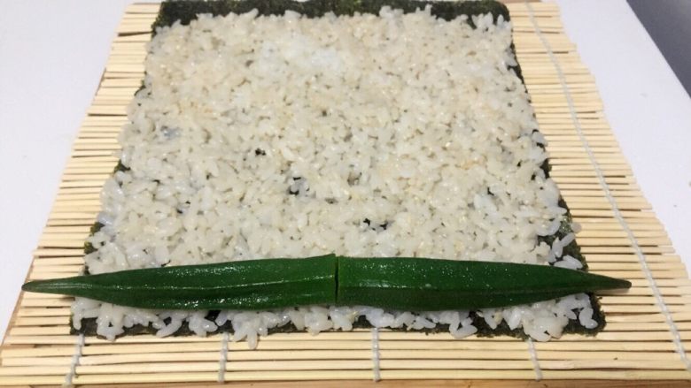 酱香味秋葵寿司(纯素版),放两根秋葵在米饭一端,用竹席卷上一点