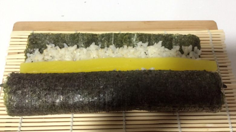 酱香味秋葵寿司(纯素版),打开竹席放一根大根,继续用竹席卷上,并用力