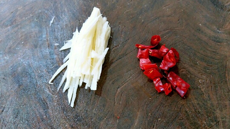 泥蒿炒腊肉,姜在案板上切细丝,干辣椒切成段,然后把干辣椒里面的籽去除,以免炒制菜肴时影响美观。