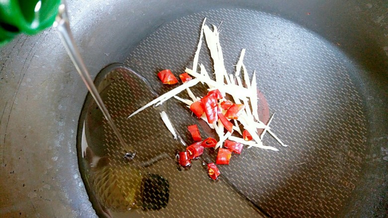 泥蒿炒腊肉,锅洗净抹干水分,把姜丝和辣椒段倒入锅内,接着加食用油十克左右。然后开小火把姜丝和辣椒段炒香。