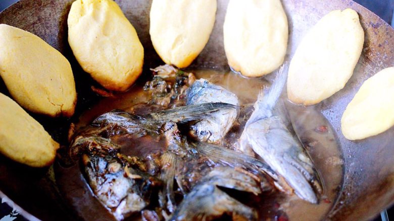 鱼头锅片片#烟台特色#,鲅鱼头烧开后、把醒发好的玉米团做成圆形薄饼子,烀至锅边、如图