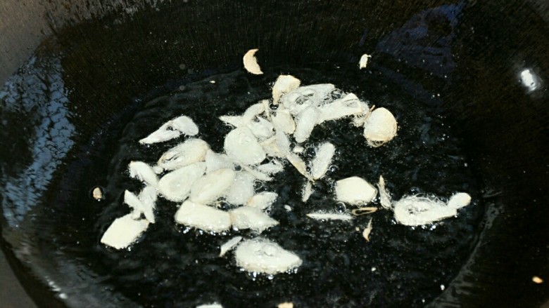 青椒炒豆腐皮,锅中油热后放蒜片爆香。