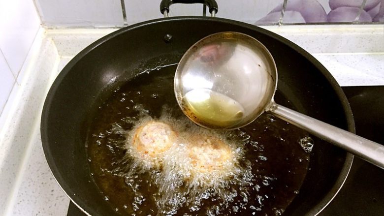 红烧狮子头,把油烧热,下入大丸子炸至外壳变硬并定型,要使用中大火。因为丸子会浮起来,用勺子舀起热油不断地淋大丸子顶部,这样它的成熟度才会保持一致。