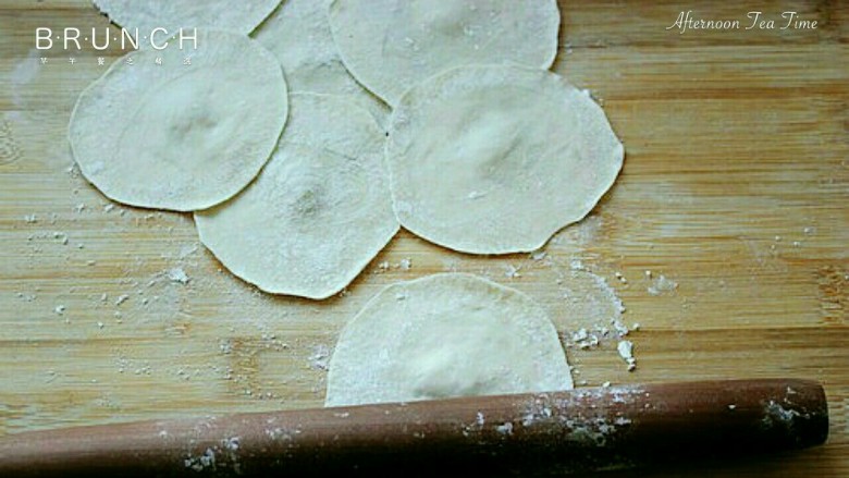 元宝饺子,压面团:洒上面粉,把每个面团用手压扁,再用擀面杖擀成面皮(注意中间厚边薄,防止漏)