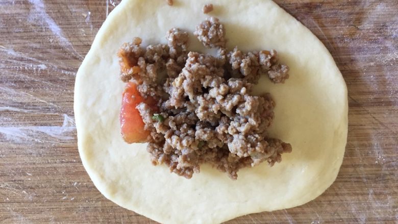 私享·番茄牛肉包,把面团擀成圆形薄片(中间稍厚,四周较薄),放入之前做好的馅料,摊在手上向中间合拢,扭成球形
