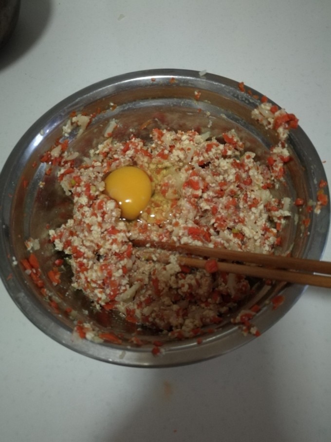 杂蔬猪肉鳕鱼蒸卷,打一颗鸡蛋，顺时针将馅料搅拌均匀。