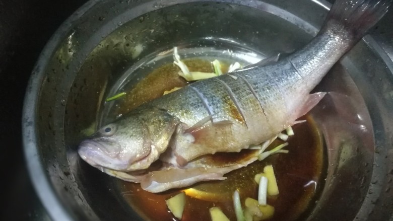 锡纸包烤鲈鱼,加入少许糖、盐把汤汁均匀沾满鱼身腌制15分钟,中间把鱼翻面让鱼均匀的吸收汤汁入味