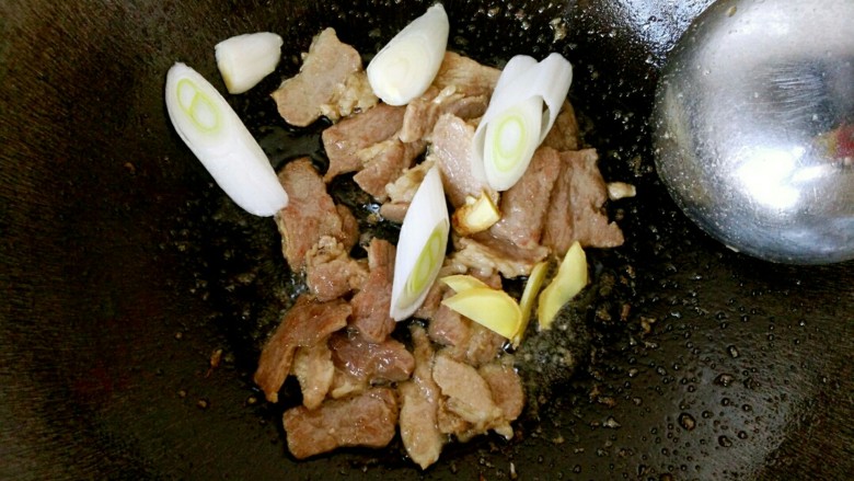 香焖油豆角,翻炒至肉片表面焦黄时,下入葱姜。